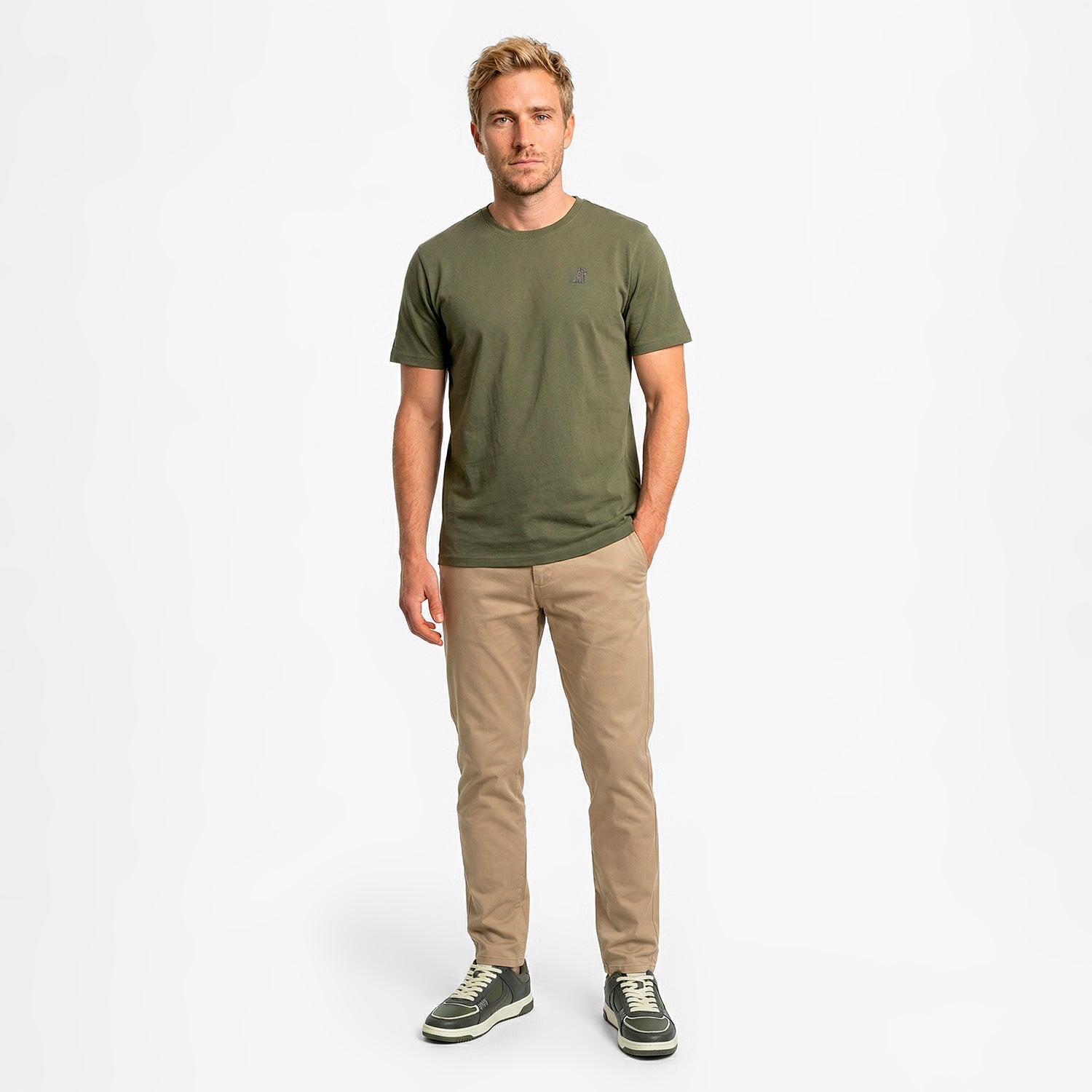 Man wearing a green t-shirt and beige pants on a white background