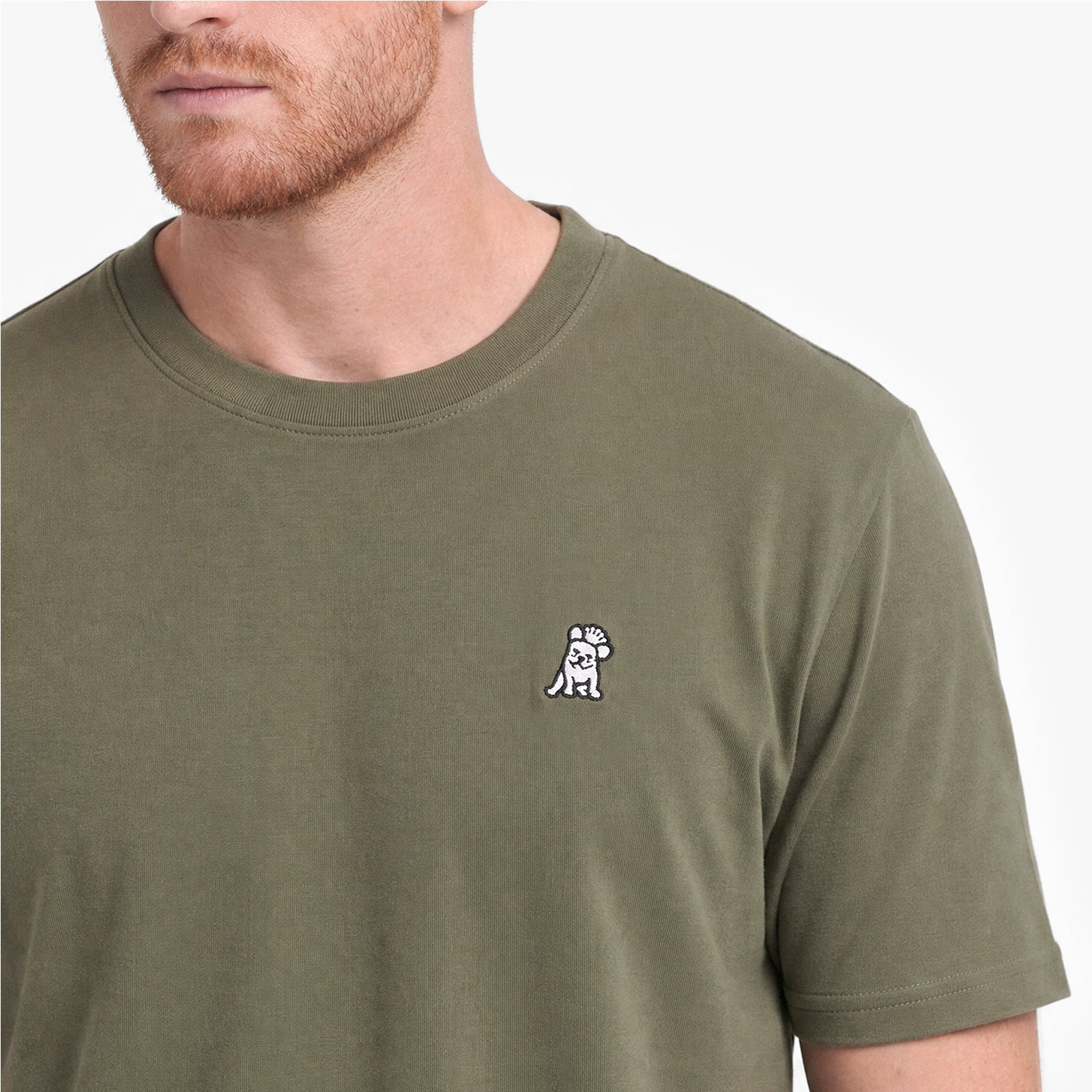 Man wearing a green t-shirt with a small logo on a white background
