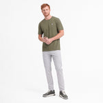 Man wearing a green t-shirt and light gray pants on a white background