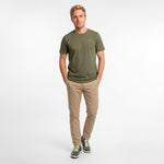 Man wearing a green t-shirt and beige pants on a white background