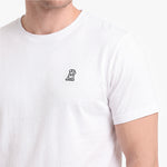 A close-up of a person wearing a white short-sleeve crewneck t-shirt with a small embroidered logo