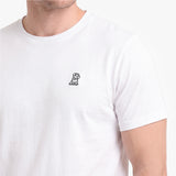 A close-up of a person wearing a white short-sleeve crewneck t-shirt with a small embroidered logo