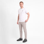 A man wearing a white short-sleeve crewneck t-shirt with a small black logo, paired with light gray trousers