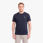 A man wearing a navy blue short-sleeve crewneck t-shirt with a small white embroidered logo