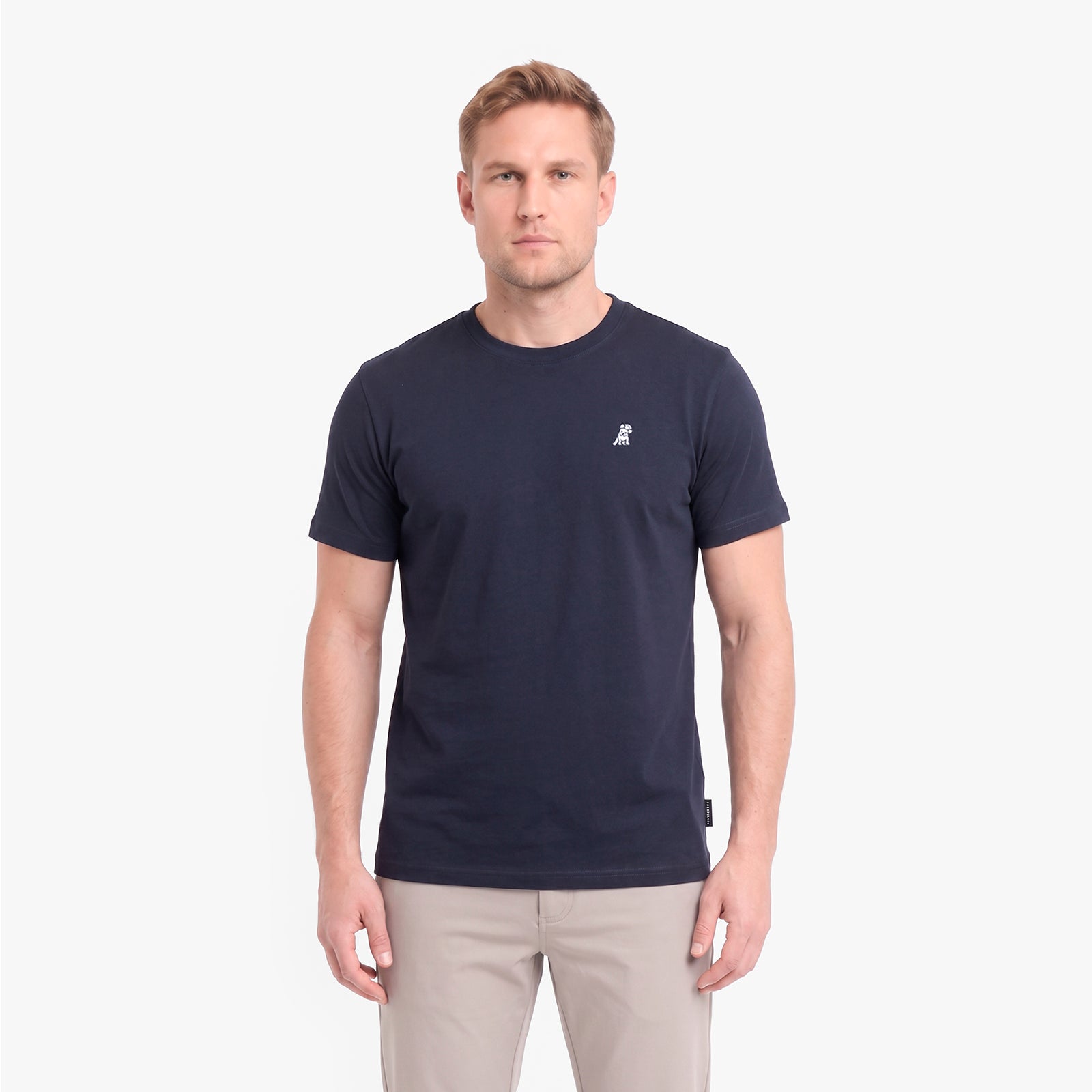 A man wearing a navy blue short-sleeve crewneck t-shirt with a small white embroidered logo