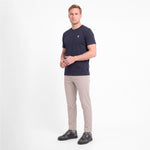 A man modeling a short-sleeve crewneck t-shirt in navy blue with a small white logo, paired with beige trousers