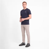 A man modeling a short-sleeve crewneck t-shirt in navy blue with a small white logo, paired with beige trousers