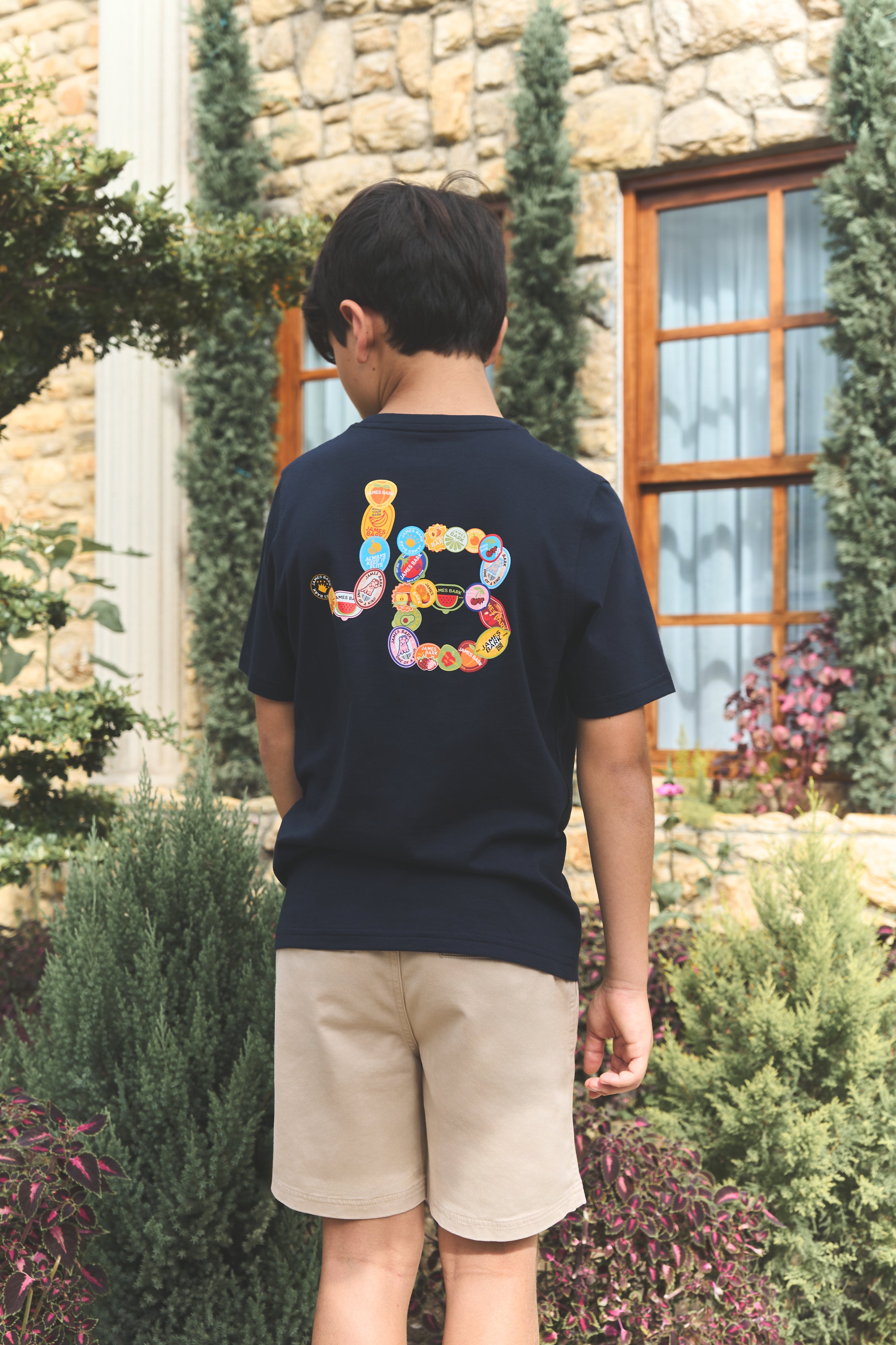 Person wearing a navy blue t-shirt with colorful letters in an outdoor setting