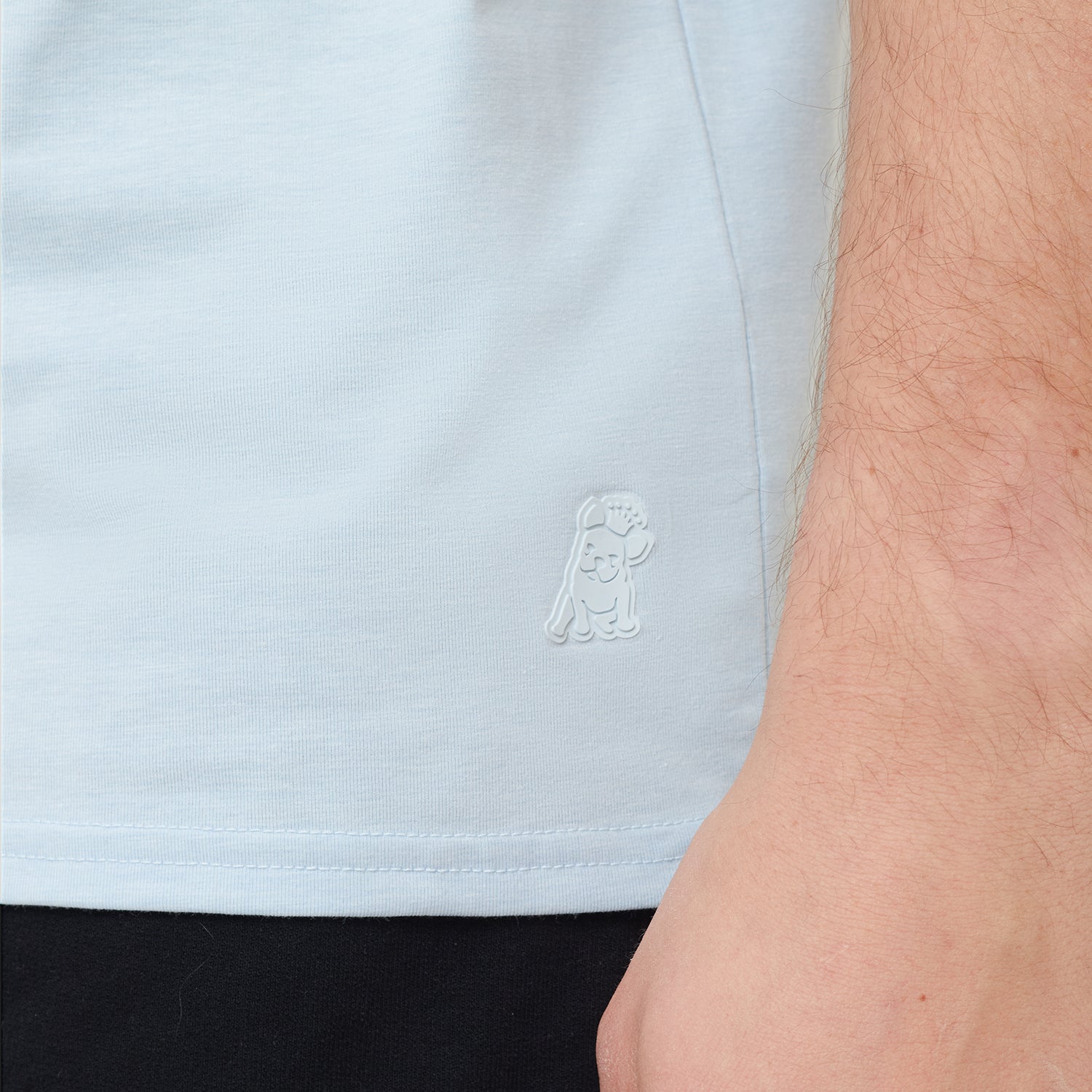 Light blue shirt with a logo on the chest worn by a person.