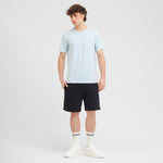 Man wearing a light blue t-shirt and black shorts on a white background
