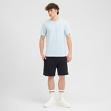 Man wearing a light blue t-shirt and black shorts on a white background