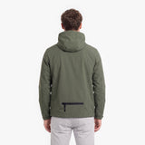 A man viewed from the back wearing an olive green hooded jacket with a black zippered pocket on the lower back, paired with light gray pants