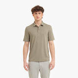 Man wearing a beige polo shirt and light gray pants on a white background