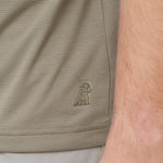 Close-up of beige shorts with a logo on the side, showing skin texture.