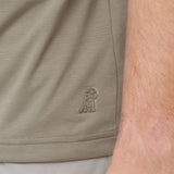 Close-up of beige shorts with a logo on the side, showing skin texture.