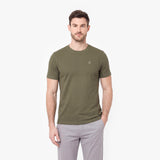 Man wearing an olive green t-shirt and light gray pants on a white background