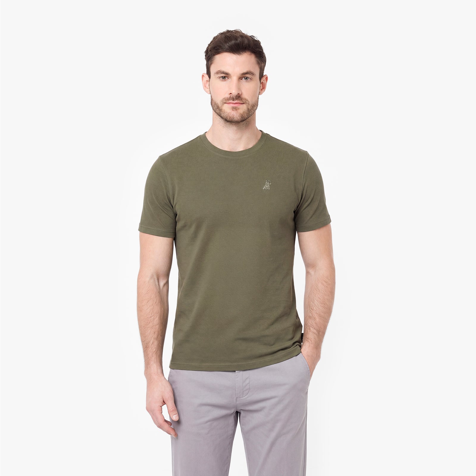 Man wearing an olive green t-shirt and light gray pants on a white background