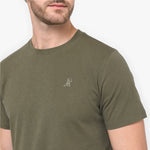 Man wearing a green t-shirt with a small logo on a white background