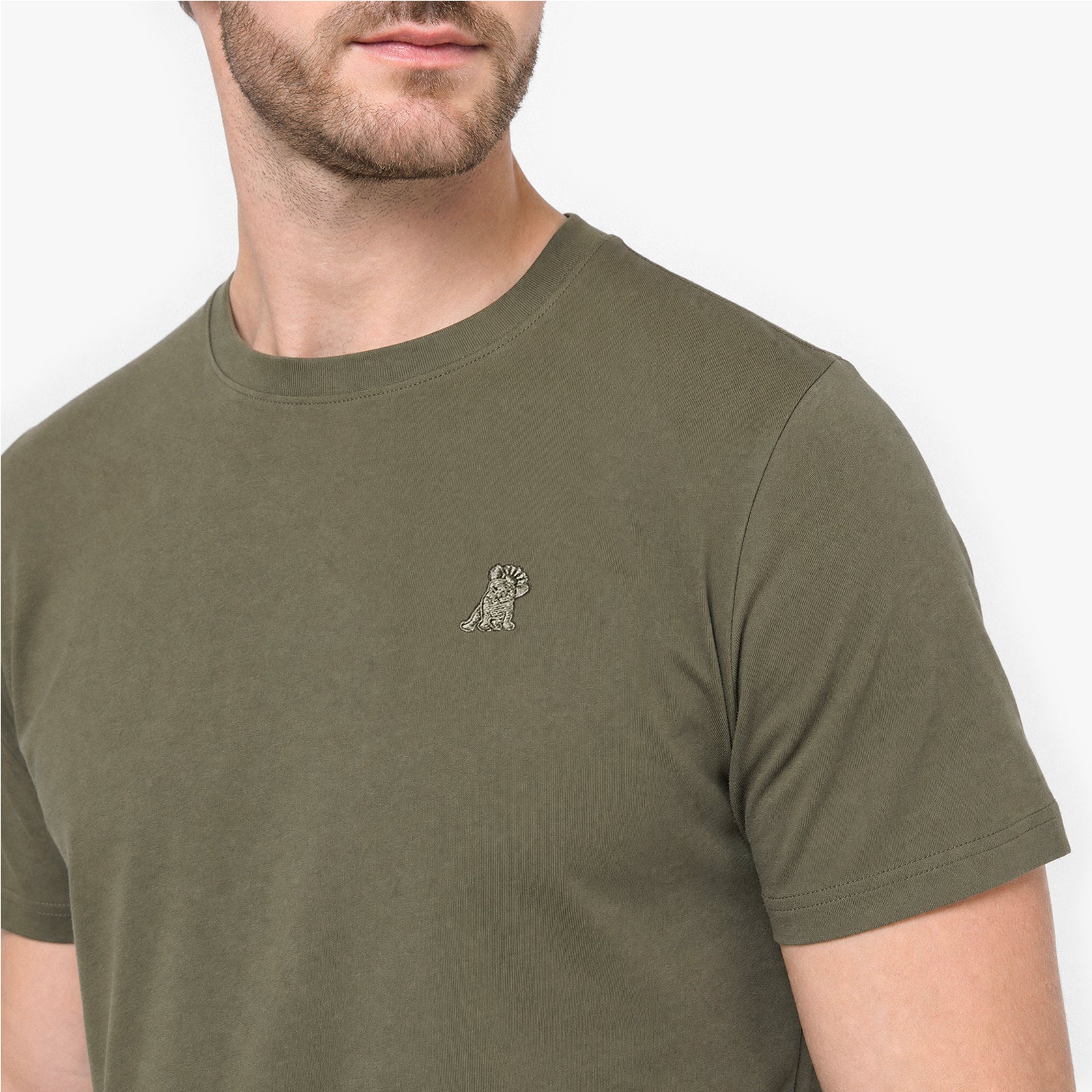 Man wearing a green t-shirt with a small logo on a white background