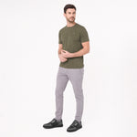Man wearing an olive green t-shirt and gray pants on a white background