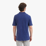 Back view of a man wearing a blue polo shirt on a white background