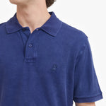 Close-up of a blue polo shirt with a small logo on a white background