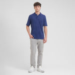 Man wearing a blue polo shirt and gray pants on a white background