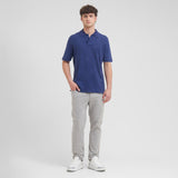 Man wearing a blue polo shirt and gray pants on a white background