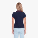 Back view of a woman wearing a navy polo with an embroidered dog logo on a white background