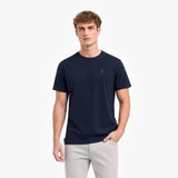 Man wearing a navy blue t-shirt with a small logo on a white background