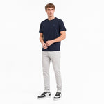 Man wearing a navy t-shirt and light gray pants on a white background