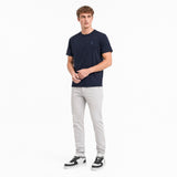 Man wearing a navy t-shirt and light gray pants on a white background