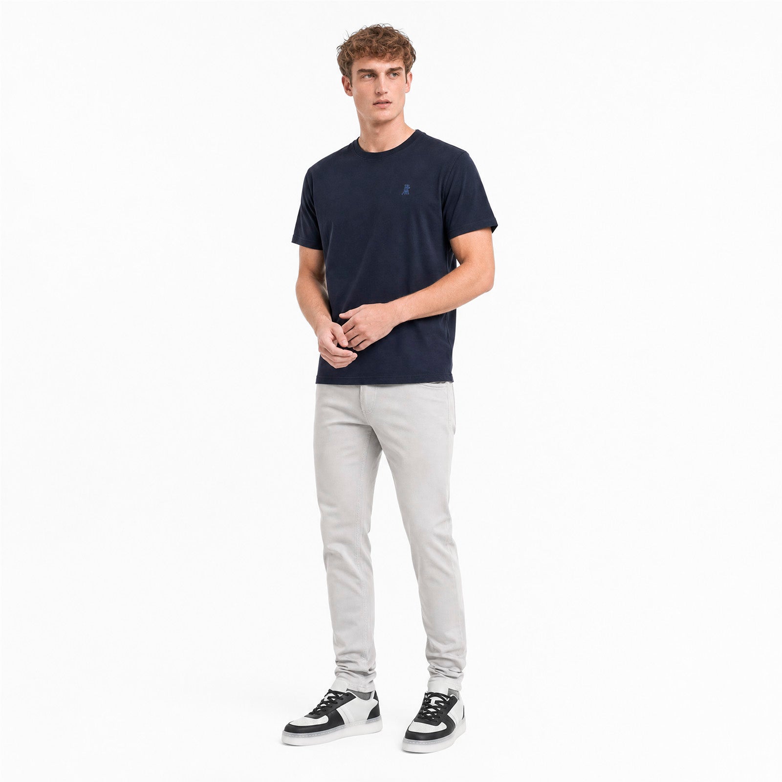 Man wearing a navy t-shirt and light gray pants on a white background