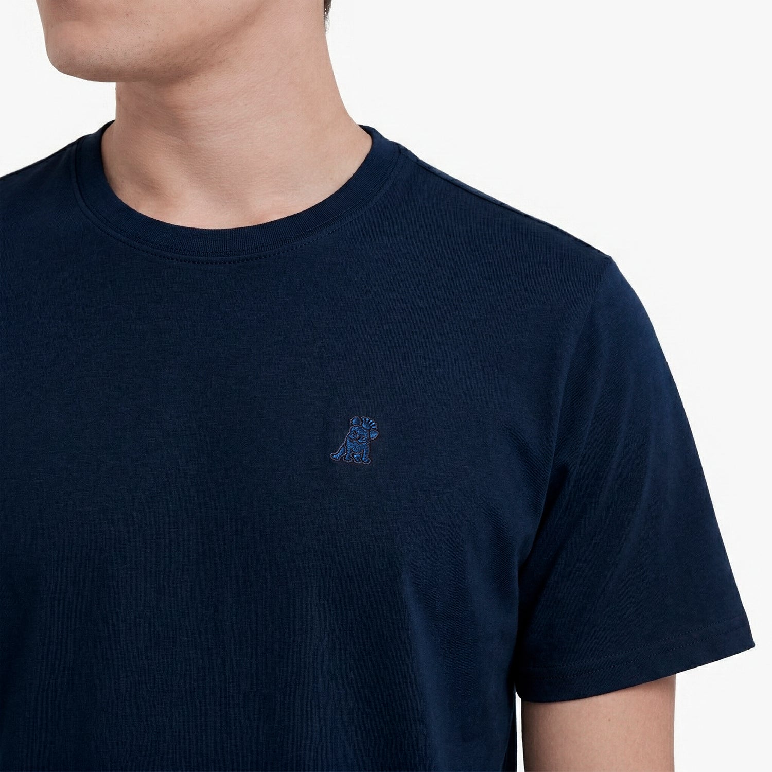 Close-up of a navy blue t-shirt with a small logo on a white background