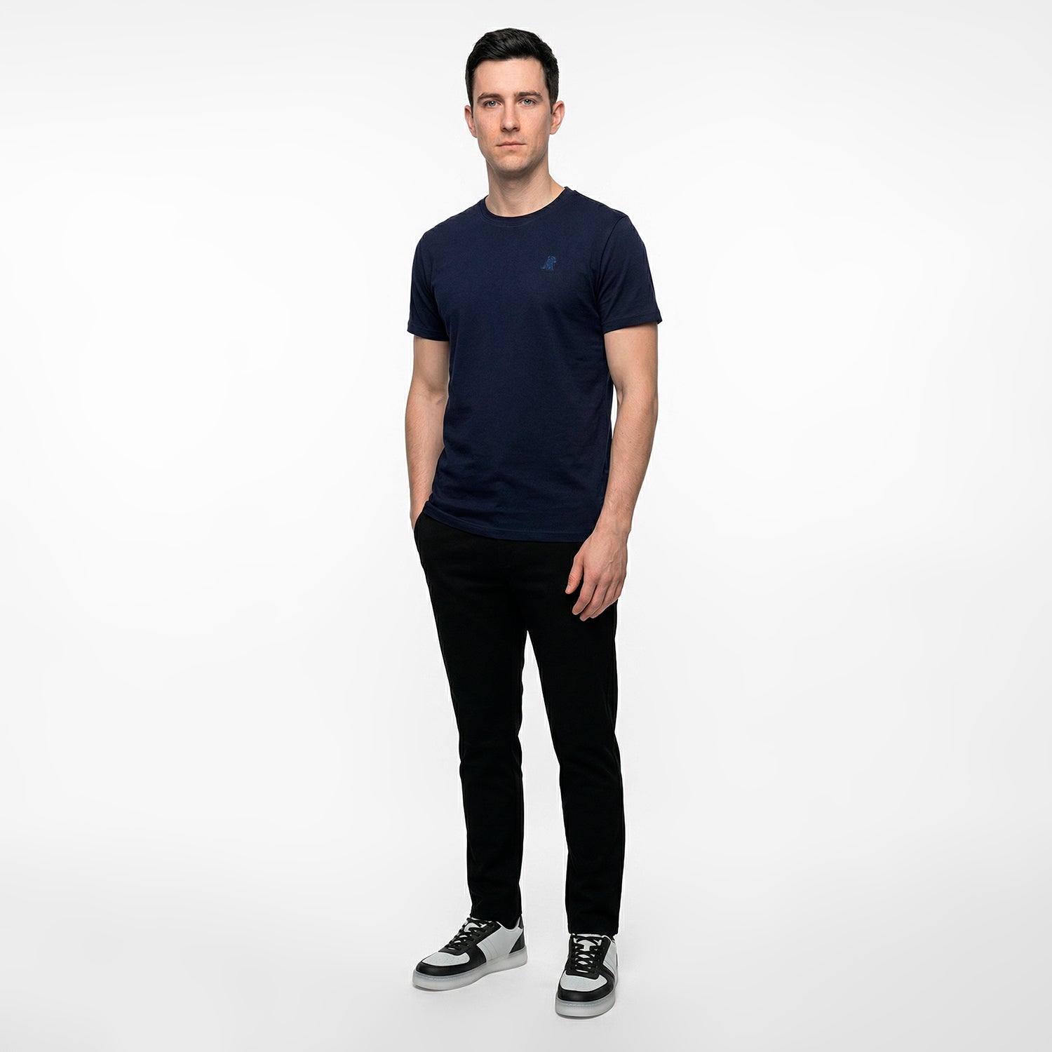 Man wearing a navy blue t-shirt and black pants on a white background