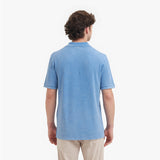 Back view of a man wearing a light blue polo shirt on a white background