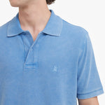 Close-up of a blue polo shirt with a small logo on a white background