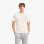 Man wearing a white t-shirt with a small logo on a white background