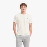 Man wearing a white t-shirt with a small logo on a white background