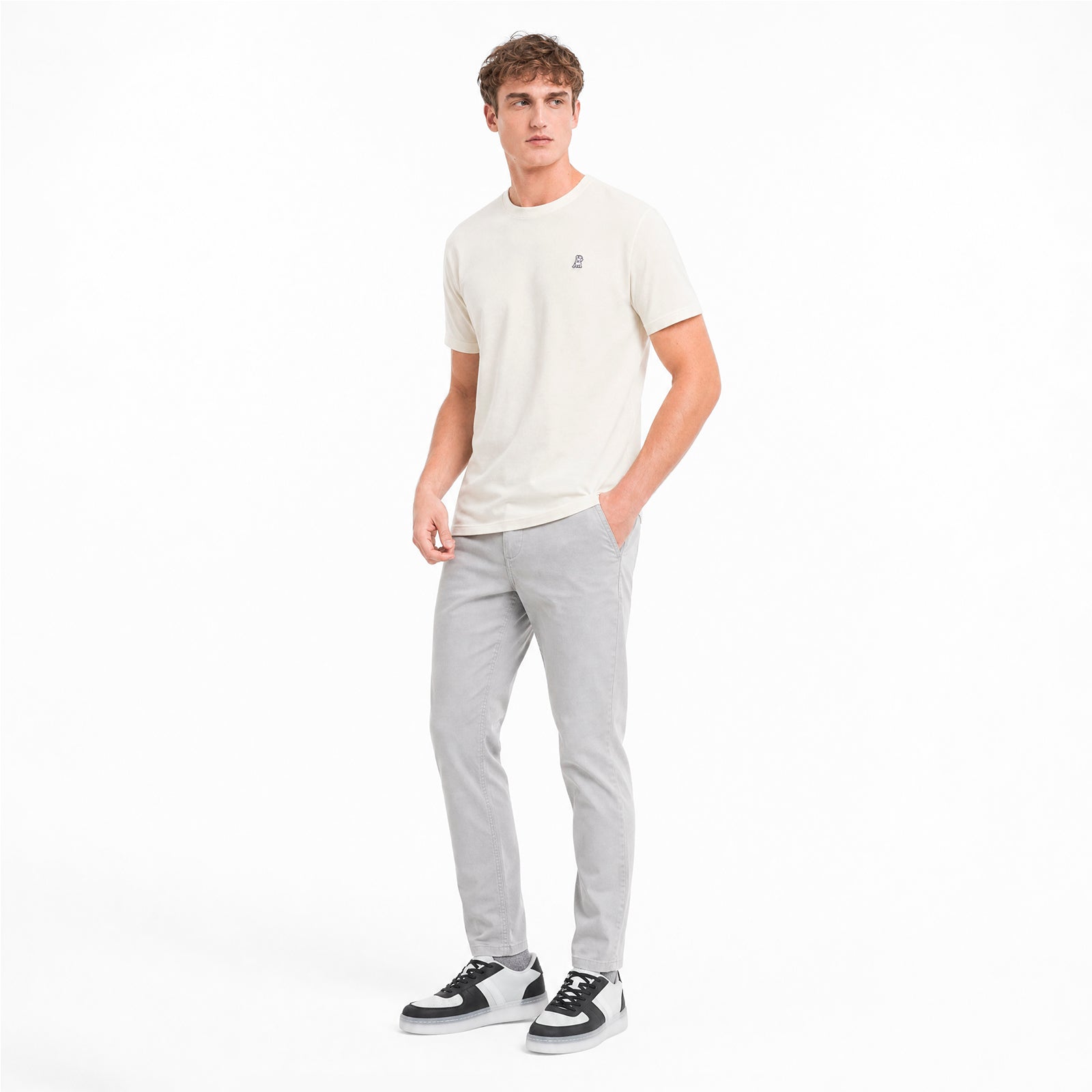 Man wearing a white t-shirt and gray pants on a white background