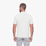 Man wearing a white polo shirt and light gray pants on a white background