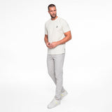 Man wearing a white t-shirt and gray pants on a white background