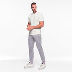 Man wearing a white t-shirt and gray pants on a white background