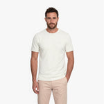 Man wearing a white t-shirt with a white embroidered logo on a white background