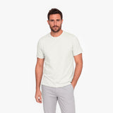 Man wearing a plain white t-shirt and light gray pants on a white background