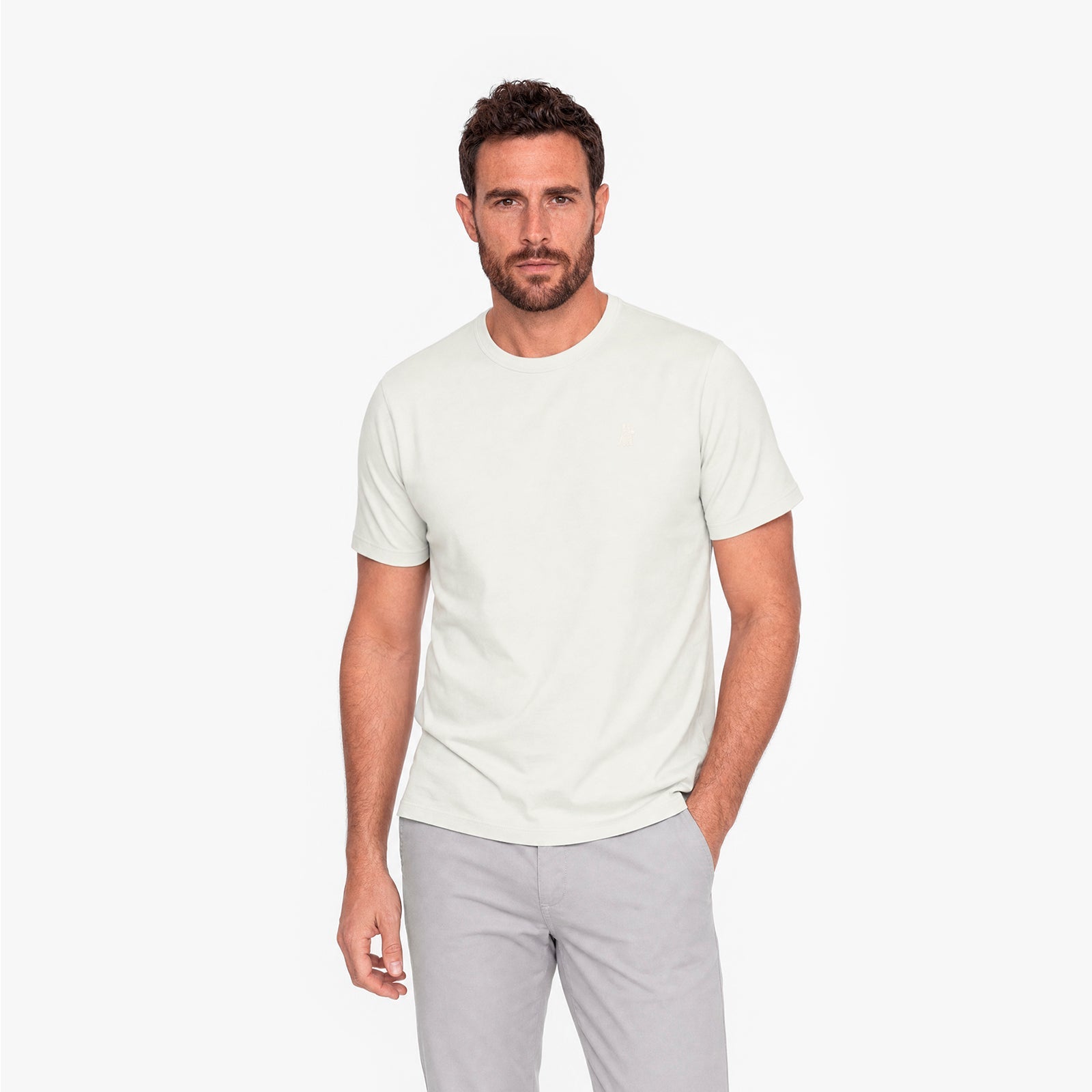 Man wearing a plain white t-shirt and light gray pants on a white background
