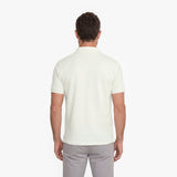 Man wearing a white polo shirt and light gray pants on a white background