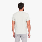 Man wearing a plain white t-shirt and light gray pants on a white background