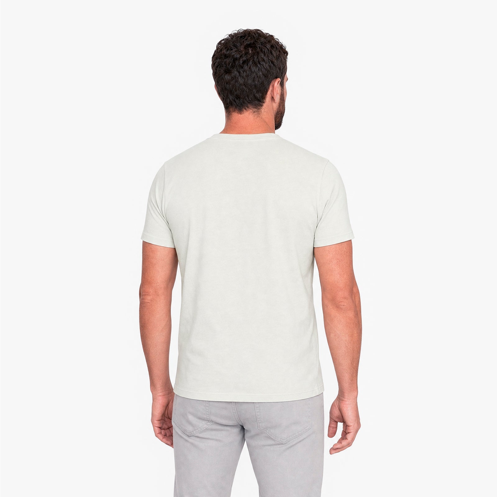 Man wearing a plain white t-shirt and light gray pants on a white background
