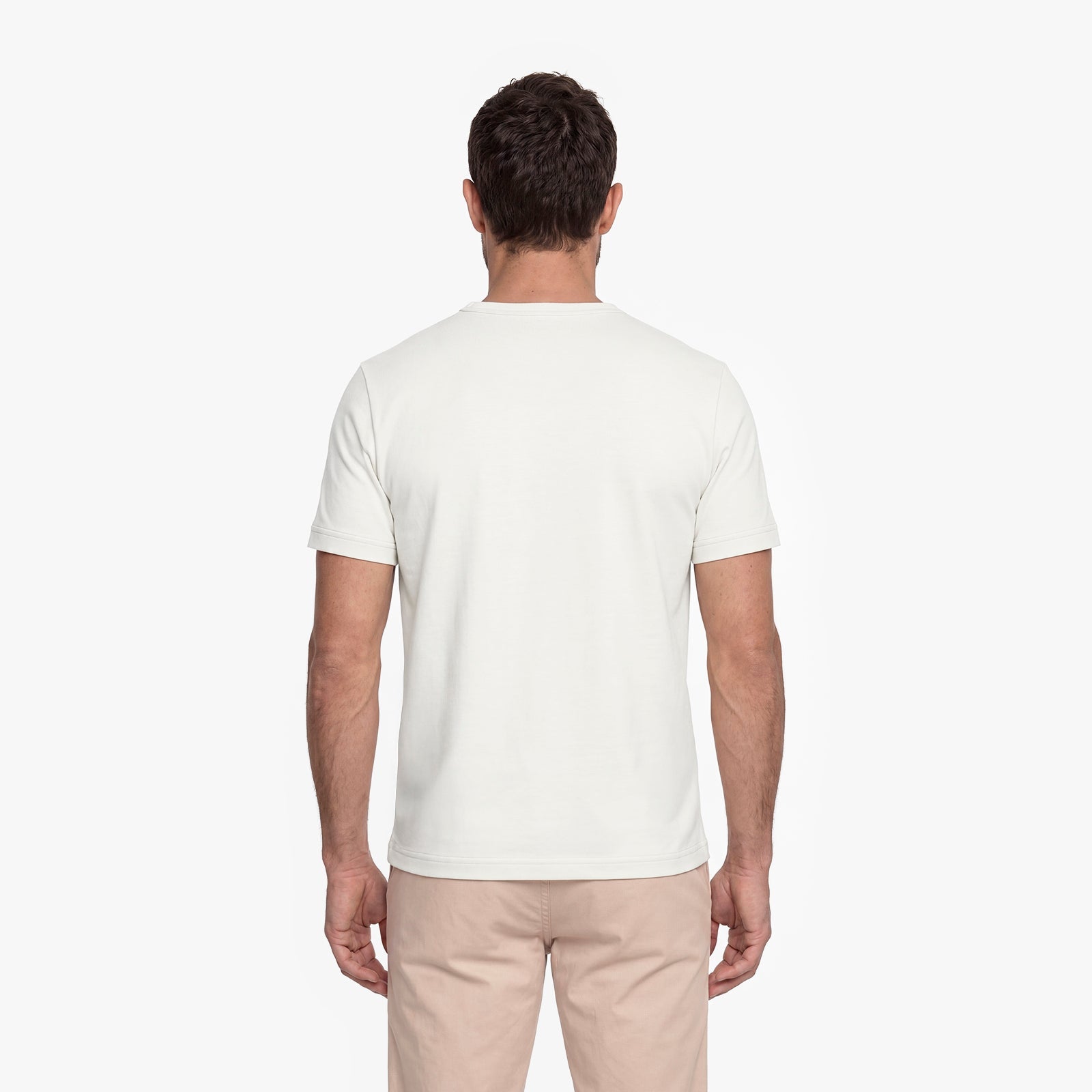 Man wearing a plain white t-shirt and beige pants on a white background